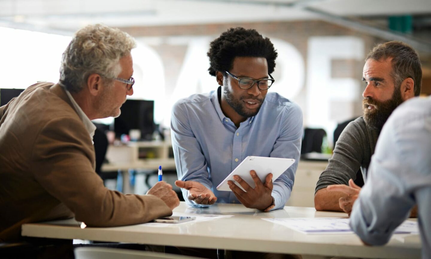 Man presenting to colleagues on a tablet