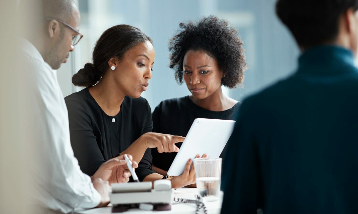 Two professional women discussing work on a tablet in a meeting