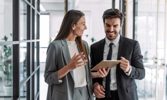 Man and woman laugh looking at a tablet
