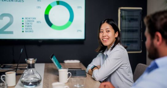 smiling woman in office presenting investment graphs