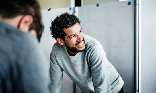 smiling-mixed-race-man-in-front-of-a-whiteboard-in-an-office